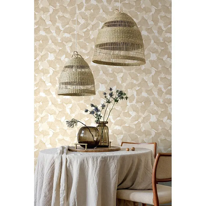 Marburg Boho Vliestapete Floral - Beige, Floral, 10,05 x 0,53 m - Zwei geflochtene Pendelleuchten erhellen einen Esstisch mit Leinentuch vor beigefarbener Ginkgoblatttapete.