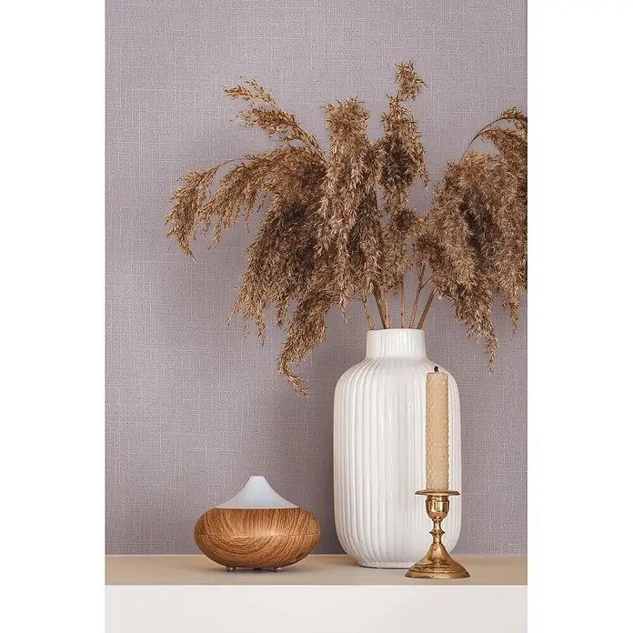 Marburg Boho Vliestapete Uni II - Violett, Uni, 10,05 x 0,53 m - Weiße gerippte Vase mit Pampasgras, Holz-Diffusor und Messingkerzenständer mit Bienenwachskerze auf einem Regal.