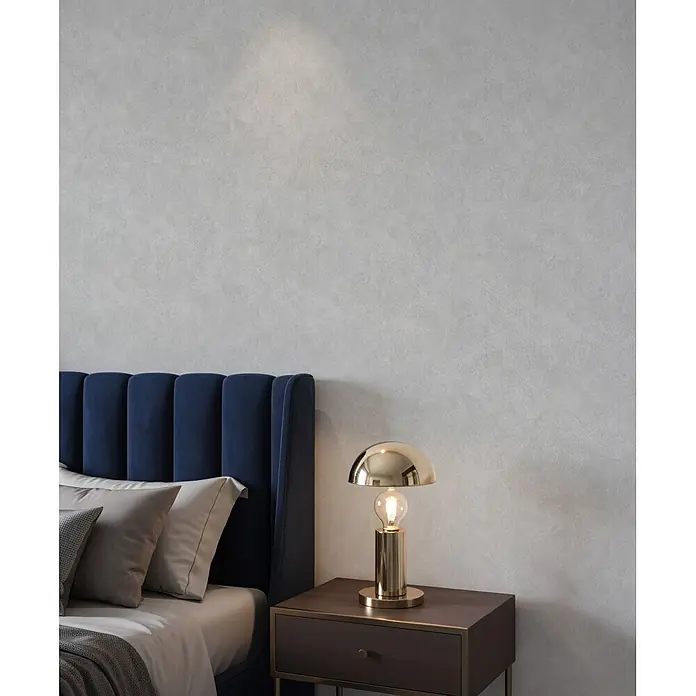 Marburg Whisper Vliestapete Putzoptik - Kalkgrau, Sonstiges, 10,05 x 0,53 m - Hellgraue strukturierte Wand, die eine ruhige Kulisse in einem Schlafzimmer mit blauem Samtbett und Goldlampe bildet.