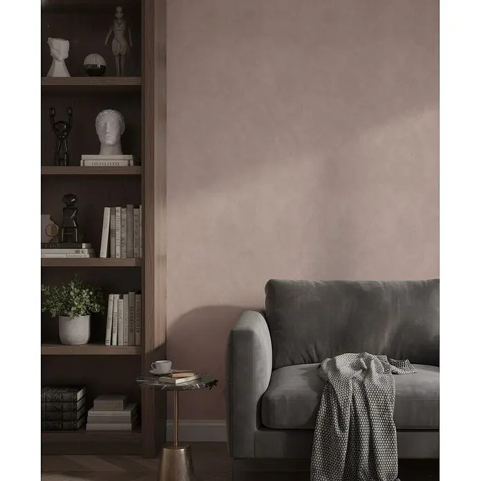 Marburg Whisper Vliestapete Putzoptik I - Braun, Sonstiges, 10,05 x 0,53 m - Ein bequemes dunkelgraues Sofa mit einer strukturierten Überwurfdecke in einem stilvollen Wohnzimmer neben einem Bücherregal.