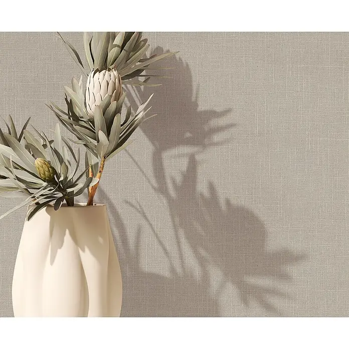 Marburg Boho Vliestapete Uni I - Naturbeige, Uni, 10,05 x 0,53 m - Cremefarbene Vase mit strukturiertem Design und zwei Proteablüten, eine offen, eine Knospe, wirft Schatten auf eine beige Wand.