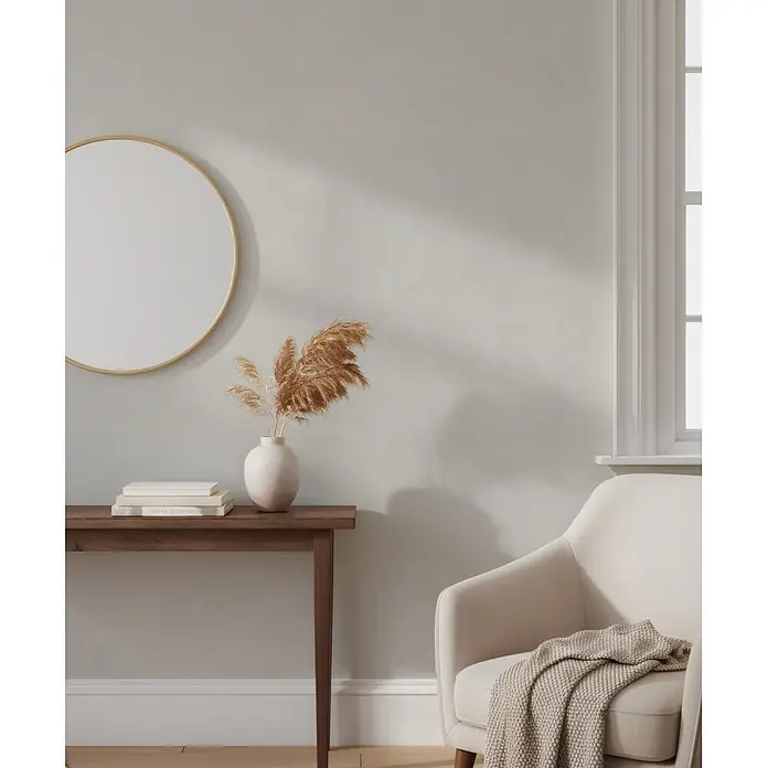 Marburg Whisper Vliestapete Putzoptik I - Beige, Sonstiges, 10,05 x 0,53 m - Ein runder, goldgerahmter Spiegel über einem Holzkonsolentisch mit Pampasgras und Büchern, neben einem cremefarbenen Sessel.