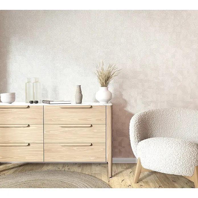 Marburg Whisper Vliestapete Grafik I - Weiß-Beige, Grafisch, 10,05 x 0,53 m - Eine helle Holzkommode mit weißer Platte und ein bequemer cremefarbener Bouclé-Sessel in einem Raum.