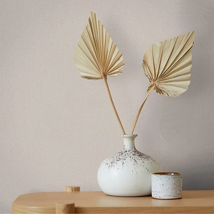 Marburg Whisper Vliestapete Uni I - Beige-Braun, Uni, 10,05 x 0,53 m - Weiße gesprenkelte Keramikvase mit getrockneten Palmblättern und kleiner Keramikschale auf hellem Holztisch.