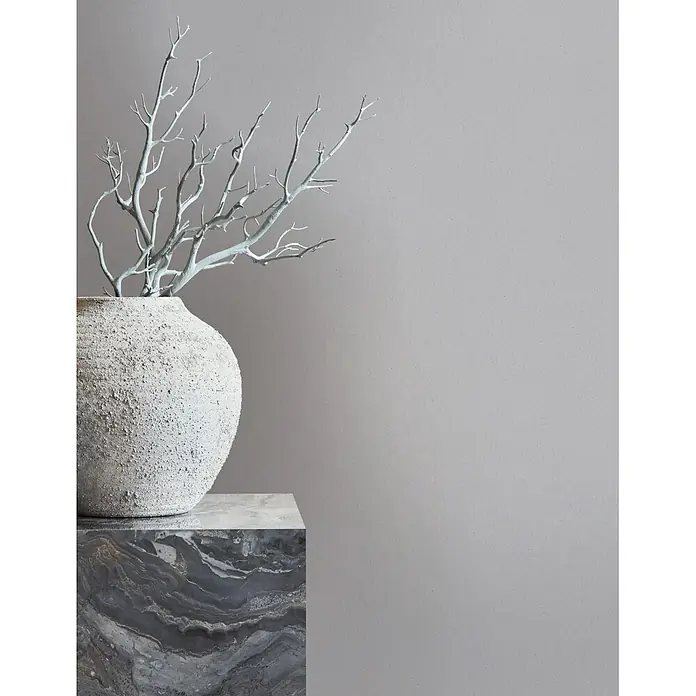 Marburg Whisper Vliestapete Uni - Grau, Uni, 10,05 x 0,53 m - Strukturierte hellbeige Vase mit hellblauen Zweigen auf einem dunklen Marmorsockel.