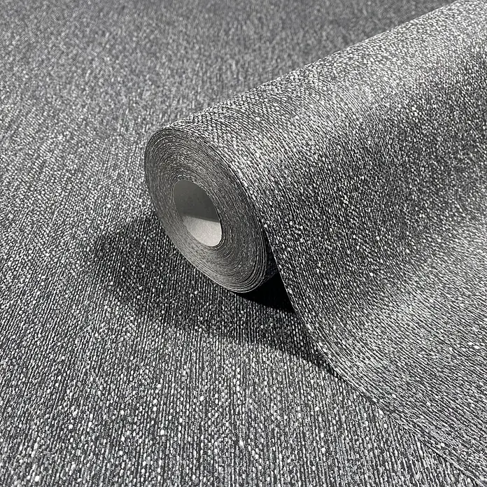Marburg Vliestapete Novamur Naomi Uni II - Schwarz, Uni, 10,05 x 0,53 m - Dunkelgraue, texturierte Tapetenrolle mit weißen Sprenkeln, teilweise abgerollt, zeigt ein gesprenkeltes Gewebemuster.