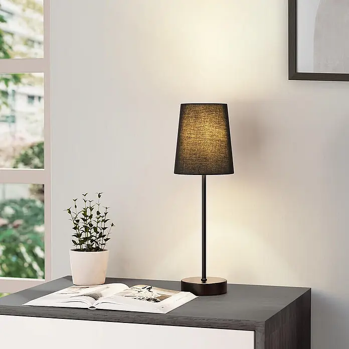Home Deluxe Tischleuchte VANA - 40 W, L x B x H: 13 x 13 x 40 cm, Schwarz, Schwarz, E14 - Dunkle Tischlampe mit Textilschirm auf einem Holztisch, warmes Licht spendend, neben einem geöffneten Buch.