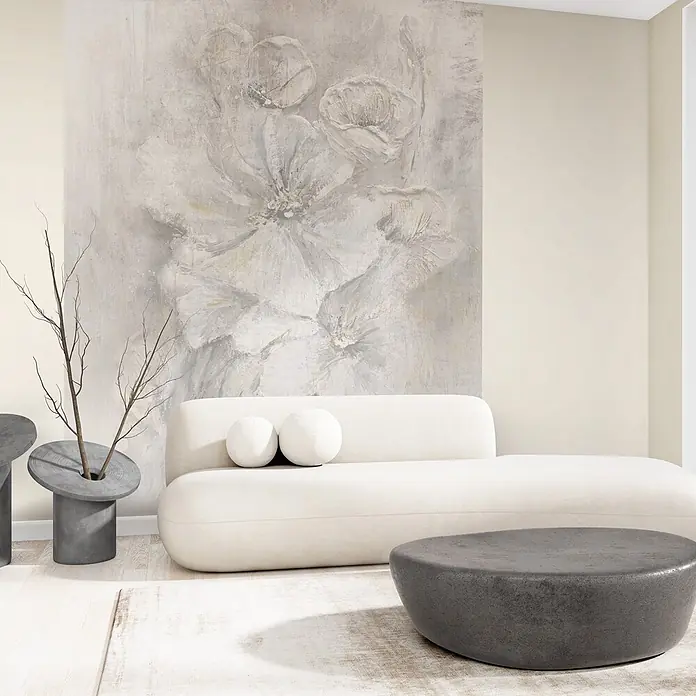 Marburg Whisper Vliestapete Uni - Beige, Uni, 10,05 x 0,53 m - Minimalistisches weißes Sofa, dunkler grauer Betontisch und passende Pflanzgefäße vor einer Wand mit texturierter weißer Blumenkunst.