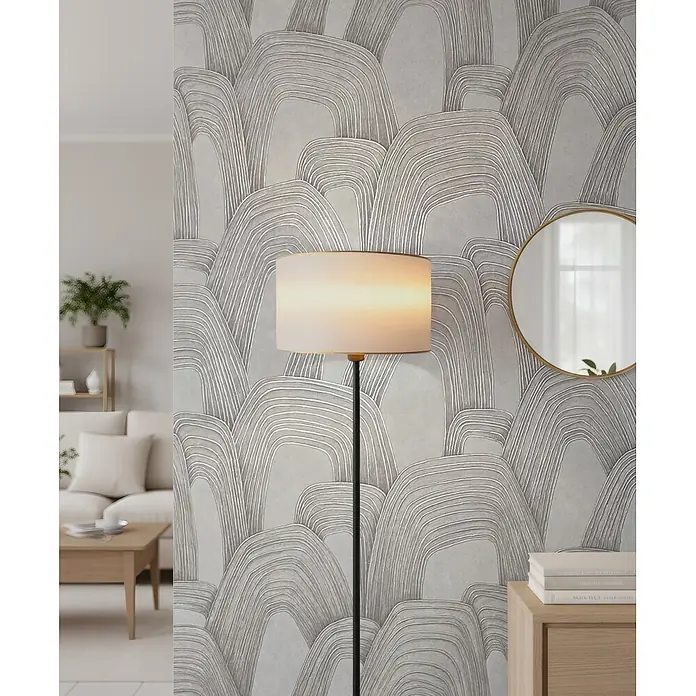 Marburg Whisper Vliestapete Grafik - Grau-Beige, Grafisch, 10,05 x 0,53 m - Graue Tapete mit texturierten, abstrakten weißen Bogenmustern, an einer Wohnzimmerwand hinter einer Lampe sichtbar.