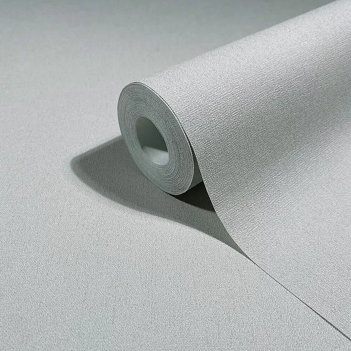 Marburg Whisper Vliestapete Uni I - Grau, Uni, 10,05 x 0,53 m - Rolle hellgraue, texturierte Tapete, teilweise ausgerollt, die ihre stoffähnliche Oberfläche zeigt.