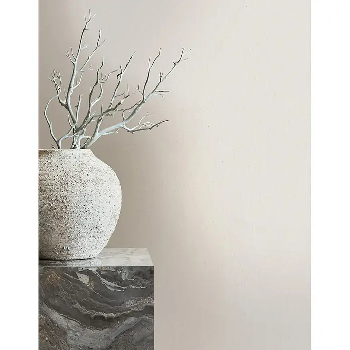 Marburg Whisper Vliestapete Uni I - Creme, Uni, 10,05 x 0,53 m - Strukturierte Keramikvase mit hellen Zweigen auf einem dunklen Marmorsockel.