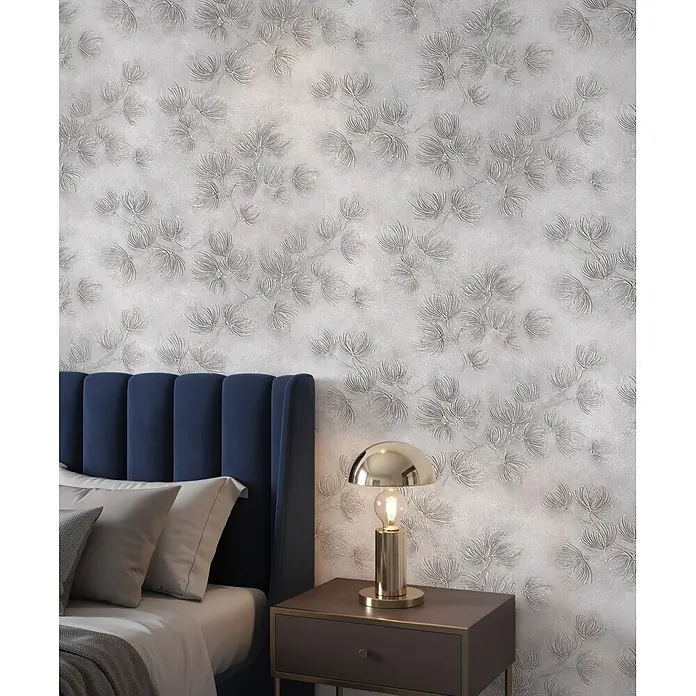 Marburg Whisper Vliestapete Floral I - Grau, Floral, 10,05 x 0,53 m - Texturierte silberne Tapete mit detailreichem Blumenmuster, die eine Schlafzimmerwand hinter einem blauen Samt-Kopfteil verschönert.