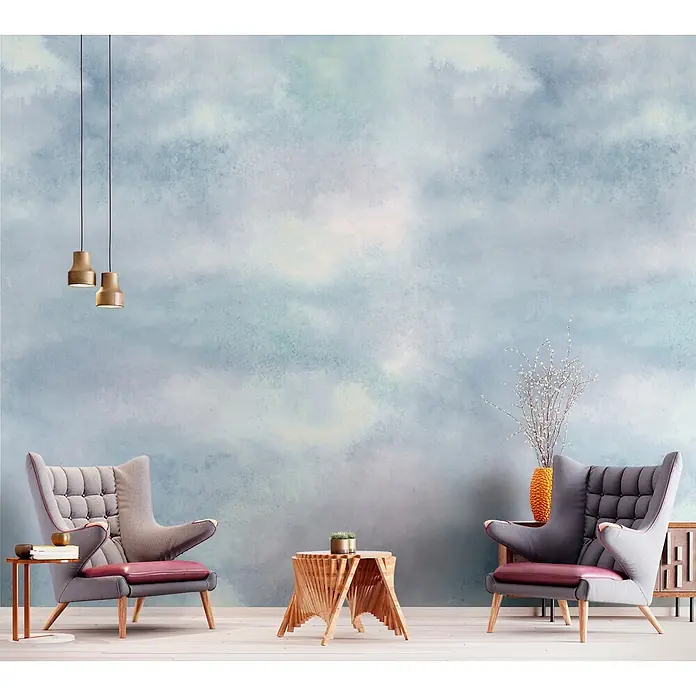 Marburg Smart Art Aspiration Fototapete Wolken I - B x H: 212 x 270 cm, Vlies, Blau - Zwei graue Sessel mit lila Kissen und Holzakzenten stehen symmetrisch in einem Raum mit wolkenmusteriger Wand.