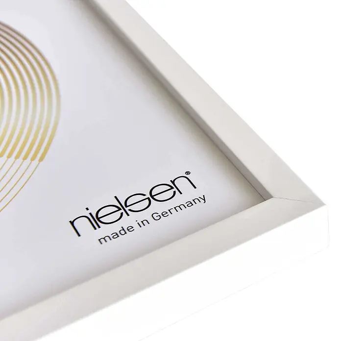 Nielsen Holzrahmen Vinyl Frame - 31,4 x 31,6 cm, Weiß - Nahaufnahme eines weißen Bilderrahmens mit weißem Passepartout, bedruckt mit 'nielsen made in Germany' und goldenem Design.