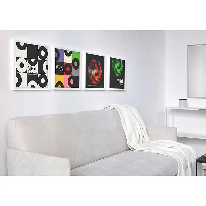 Nielsen Holzrahmen Vinyl Frame - 31,4 x 31,6 cm, Weiß - Ein hellgraues Sofa mit einer weißen Decke, platziert in einem Wohnzimmer unter vier gerahmten Bildern.