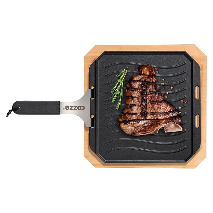 Cozze Grillpfanne - L x B: 30 x 30 cm, Höhe: 1 cm, Gusseisen - Cozze Gusseisen-Grillpfanne mit Holzbrett und Metallspatel, mit gegrilltem T-Bone-Steak.