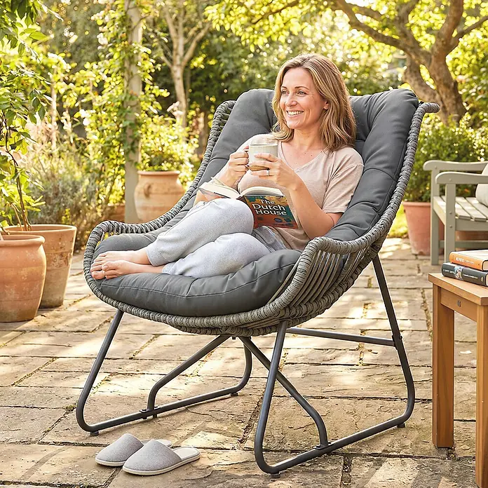 Outsunny Garten-Loungesessel - Stahl, PE Rattan, Polyester, Schaumstoff, Dunkelgrau, B x T x H: 75 x 101 x 90 cm - Grauer Garten-Lounge-Sessel mit geflochtener Rattan-Optik und dunklem Metallrahmen, von einer Frau zum Entspannen im Freien genutzt.