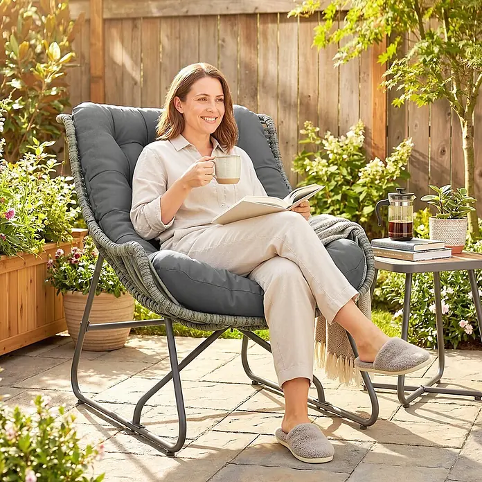 Outsunny Garten-Loungesessel - Stahl, PE Rattan, Polyester, Schaumstoff, Dunkelgrau, B x T x H: 75 x 101 x 90 cm - Grauer Outdoor-Lounge-Sessel mit dunkelgrauen Kissen, von einer Frau auf einer Terrasse mit Tasse und Buch benutzt.