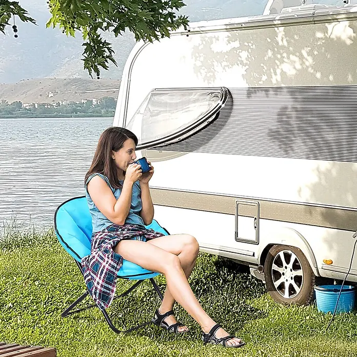 Outsunny Garten-Loungesessel - Metall, 600D-Oxfordstoff (100% Polyester), Klappbar, Blau, B x T x H: 80 x 80 x 75 cm - Blauer, klappbarer Campingstuhl mit schwarzem Gestell, von einer Frau am See neben einem Wohnwagen genutzt.