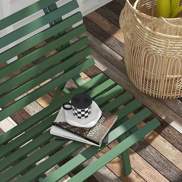 Outsunny Gartenbank - B x T x H: 67 x 67 x 79 cm, Aluminium, Grün - Grüne Lamellenbank mit Büchern und einer karierten Tasse, daneben ein Weidenpflanzer auf einem gemusterten Holzboden.