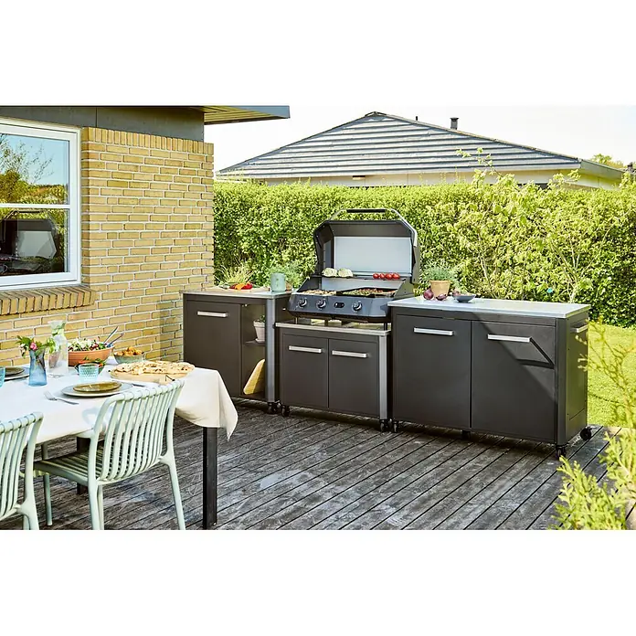 Cozze Gasgrill G 800 Combo - Grillfläche (B x T): 81,5 x 42 cm, 9,5 kW, Anzahl Brenner: 3 Stk. - Dunkelgraue Außenküche mit Edelstahlplatten, Gasgrill und Schränken auf einer Holzterrasse. Gemüse wird zum Grillen vorbereitet.