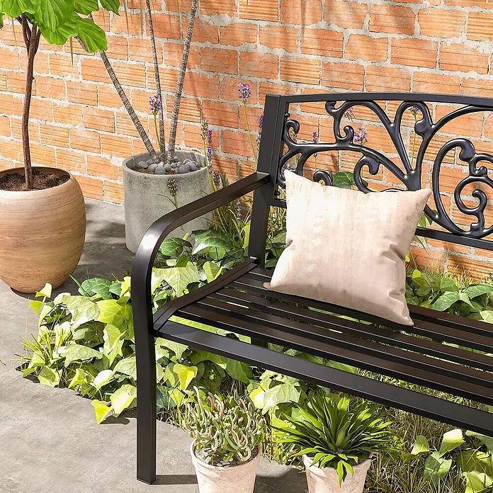 Furnicato Gartenbank pulverbeschichtet - B x T x H: 60 x 127 x 87 cm, Metall, Schwarz - Schwarze Metallgartenbank mit verzierter Rückenlehne und hellem Kissen, in einer üppigen Gartenumgebung.