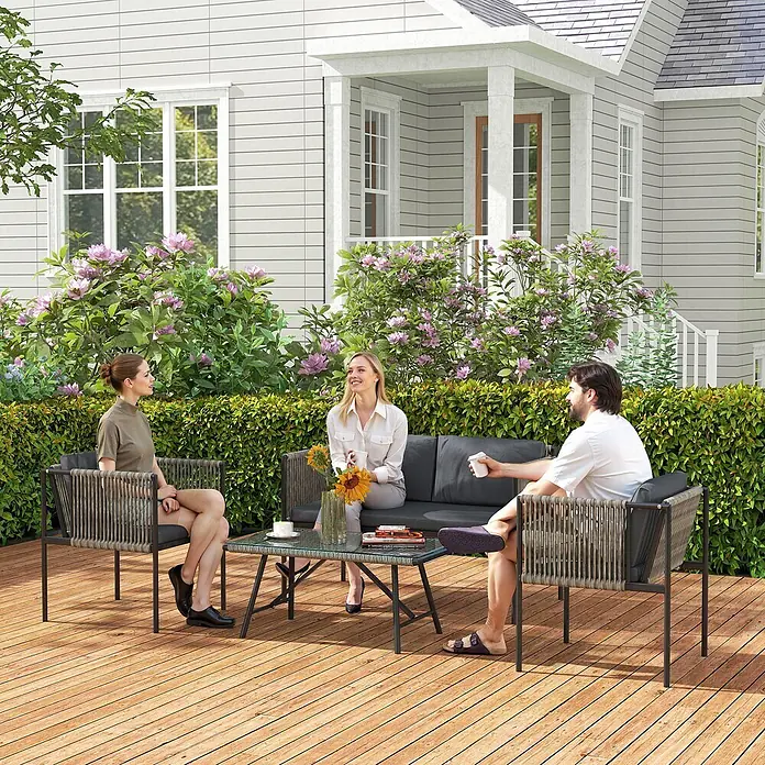 Outsunny Loungemöbel-Set - 4 -tlg., Stahl, PE-Rattan, Polyester, gehärtetes Glas, Schaumstoff, Sitzkissen, Grau - Outdoor-Loungemöbel-Set mit Sofa, zwei Stühlen und Glastisch, von drei Personen auf Holzterrasse genutzt.