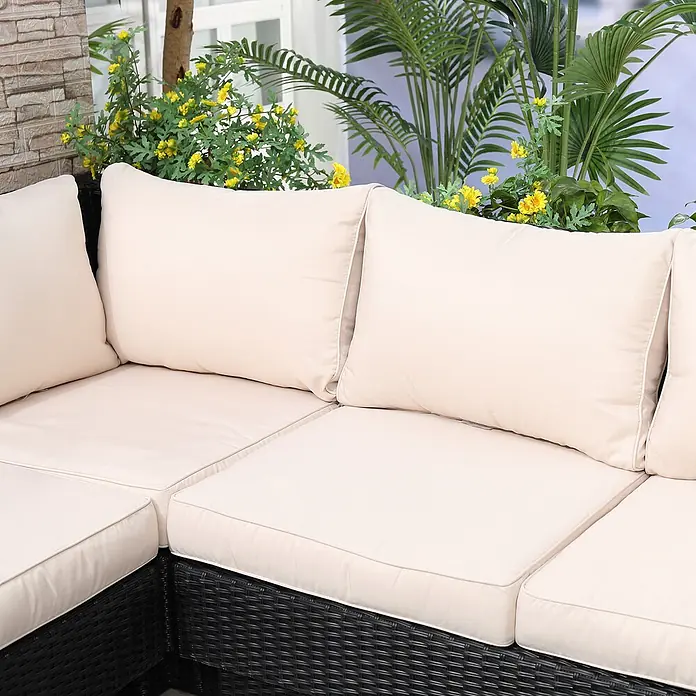 Outsunny Loungemöbel-Set - 4 -tlg., Polyrattan, Stahl, Polyester, Sitzkissen, Schwarz - Schwarzes Rattan-Outdoor-Ecksofa mit cremefarbenen Kissen, draußen zwischen Pflanzen und gelben Blumen.