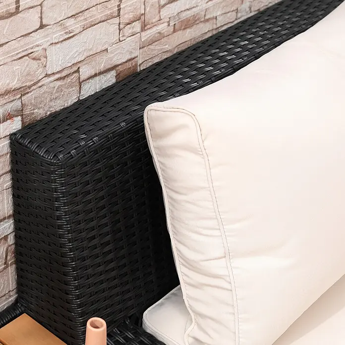 Outsunny Loungemöbel-Set - 4 -tlg., Polyrattan, Stahl, Polyester, Sitzkissen, Schwarz - Nahaufnahme schwarzer geflochtener Outdoor-Möbel mit cremefarbenem Kissen, vor einer Ziegelwand.
