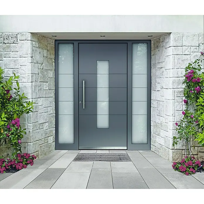 ACO Vario Bodenwanne60 x 40 cm, Polymerbeton - Modernes graues Haustür-Design mit Glaseinsätzen und seitlichen Lichtelementen, umgeben von einer Steinmauer und blühenden Pflanzen.