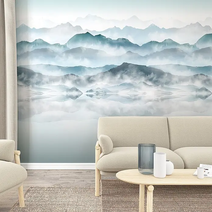 Marburg Smart Art Easy Fototapete Illustration III - B x H: 212 x 270 cm, Vlies - Wohnzimmer mit cremefarbenem Sofa und Couchtisch vor einer Wand mit einem Wandbild nebelverhangener blau-grüner Berge und einem spiegelnden See.