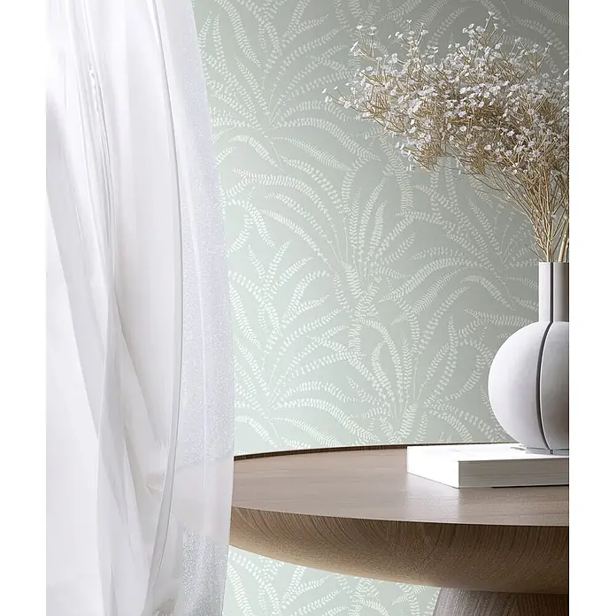 Marburg Vliestapete Novamur Oriana Floral - Grün, Floral, 10,05 x 0,53 m - Ruhiges Interieur mit hellgrüner Farn-Tapete, Holztisch mit weißer Vase, zarten weißen Blumen und einem weißen Buch. Weiche Vorhänge.