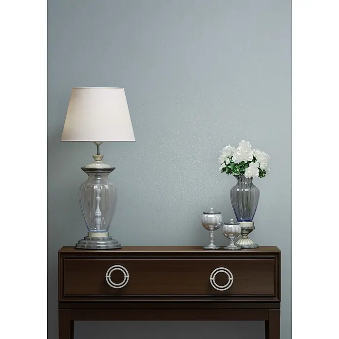 Marburg Vliestapete Novamur Naomi Uni I - Blau, Uni, 10,05 x 0,53 m - Dunkle Holzkommode mit runden Griffen, darauf eine Glaslampe, eine Vase mit weißen Blumen und silberne Zierkelche.