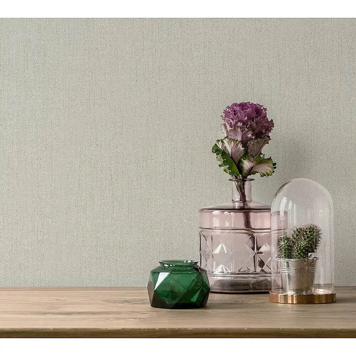 Marburg Vliestapete Novamur Leyla Uni - Grün, Uni, 10,05 x 0,53 m - Rosa Vase, einem grünen Glasgefäß und einem Kaktusarrangement auf einer Holzfläche.