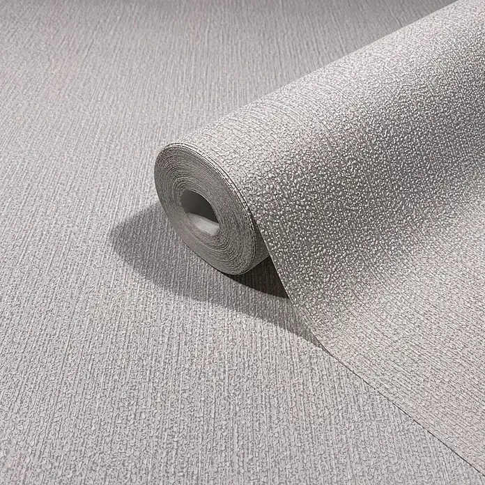 Marburg Vliestapete Novamur Mona Uni I - Grau-Beige, Uni, 10,05 x 0,53 m - Eine Rolle hellgrauer strukturierter Tapete, teilweise abgerollt, um ihr körniges Muster zu zeigen.