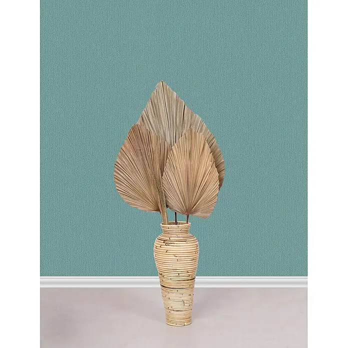 Marburg Vliestapete Novamur Mona Uni I - Grün, Uni, 10,05 x 0,53 m - Natürliche Bambusvase mit getrockneten Palmblättern vor einer türkisfarbenen Wand und hellem Boden.