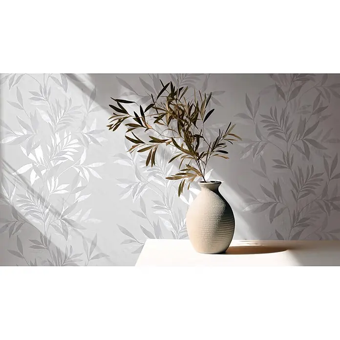 Marburg Vliestapete Novamur Mona Floral - Weiß-Grau, Floral, 10,05 x 0,53 m - Strukturierte beige Vase mit getrockneten Ästen auf einem weißen Tisch vor einer gemusterten Wand.