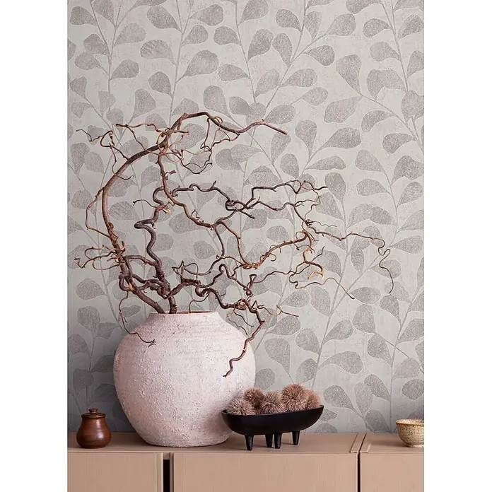 Marburg Vliestapete Novamur Naomi Floral - Grau-Beige, Floral, 10,05 x 0,53 m - Dekoration: texturierte Vase mit geschlungenen Ästen, Holztöpfchen und Schale mit Kugeln auf hellem Holzschrank.