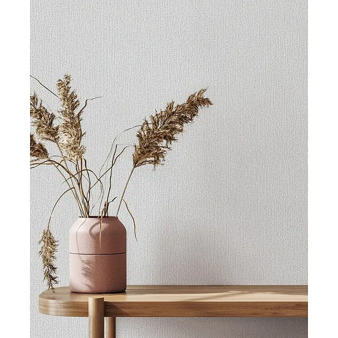 Marburg Vliestapete Novamur Mona Uni I - Grau-Beige, Uni, 10,05 x 0,53 m - Eine rosa Keramikvase mit getrocknetem Pampasgras steht auf einem hellen Holzregal.