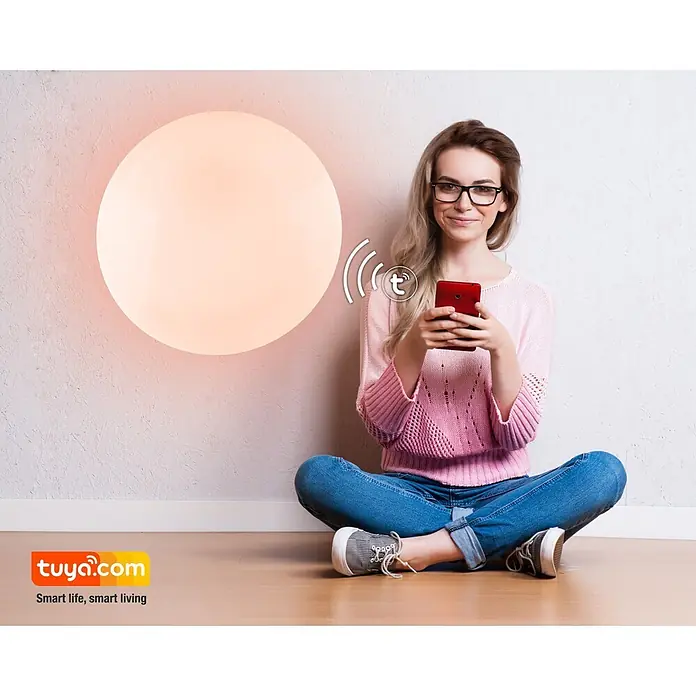 Globo LED-Deckenleuchte rund Sajama - Ø x H: 54 cm x 76 mm, 30 W - Frau steuert eine große, runde, leuchtende Smart-Leuchte mit einem roten Smartphone.