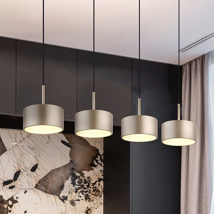 Globo LED-Pendelleuchte rund Raymond - 40 W, Warmweiß - Vier mattgoldene zylindrische Pendelleuchten hängen in einem modernen Raum und strahlen warmes Licht nach unten ab.