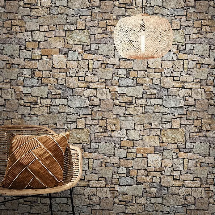 Marburg Smart Art Easy Fototapeten-Muster Mauer I - Oberflächen-Optik - Realistische Steinwandtapete in vielfältigen Naturtönen, in einem Raum mit Rattansessel und Pendelleuchte dargestellt.