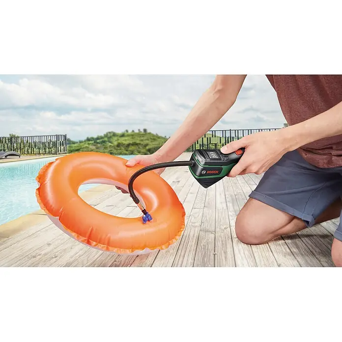 Bosch Akku-Luftpumpe Pneo Fahrradtasche - 3,6 V, Max. Druck: 10,3 bar - Person bläst einen orangefarbenen Schwimmreifen mit einer schwarz-grünen Bosch Luftpumpe auf.