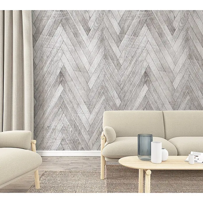 Marburg Fototapete Holzoptik - B x H: 159 mm x 270 cm, Vlies, Greige - Ein Wohnzimmer mit cremefarbenen Sofas und einem Couchtisch vor einer grauen Holz-Fischgrätwand.