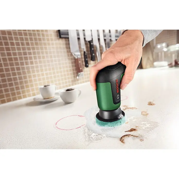 Bosch Akku-Reinigungsbürste Taydo - 3,6 V, 1 Akku, 6 -tlg. - Handgehaltener grün-schwarzer Bosch Elektroschrubber reinigt Flecken auf einer Küchenarbeitsplatte.