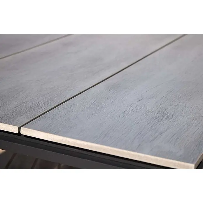Ebuy24 Gartentisch Martinus - L x B x H: 100 x 210 x 75 cm, Ø x H: 210 x 75 cm, Aluminium Nonwood, Sonstige, Grau - Nahaufnahme einer Tischplatte mit grauen Holzoptik-Keramikfliesen auf schwarzem Rahmen.
