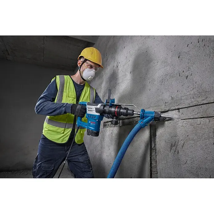 Bosch Professional Schlaghammer GSH5MX - 1.100 W, 7,8 J, Max. Schlagzahl: 2.900 U/min - Mann in PSA verwendet einen blauen Bosch Bohrhammer mit Staubabsaugung, um in eine Betonwand zu bohren.