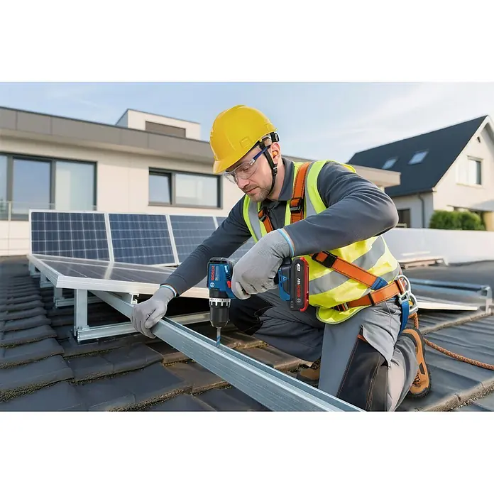 Bosch Professional AMPShare 18V Akku-Schlagbohrschrauber - 18 V, Ohne Akku, 70 Nm, Ohne L-BOXX 136 - Mann in Schutzausrüstung bohrt mit einem blau-schwarzen Bosch Akku-Bohrschrauber in einen Metallrahmen für Solarmodule auf einem Dach.