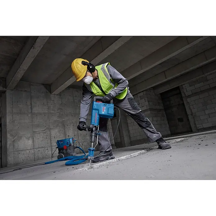 Bosch Professional Schlaghammer GSH 11 EV - 16,8 J, Max. Schlagzahl: 1.890 U/min, SDS-Max-Aufnahme - Blauer Bosch Abbruchhammer wird von einem Arbeiter zum Betonbrechen verwendet, mit Staubabsaugung.