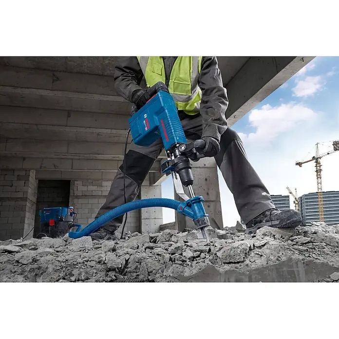 Bosch Professional Schlaghammer GSH 11 EV - 16,8 J, Max. Schlagzahl: 1.890 U/min, SDS-Max-Aufnahme - Blauer Bosch Abbruchhammer mit Staubabsaugung, von einem Arbeiter zum Zerkleinern von Beton auf einer Baustelle verwendet.